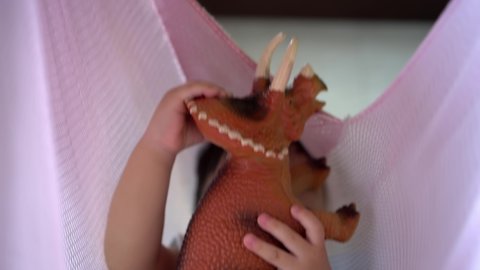Close up the hand of baby hold the triceratops dinosaur toy