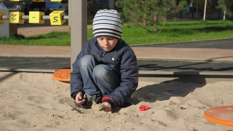 Little boy playing in sandpit on palyground and building sand castle. Concept of child development, sports and education.
