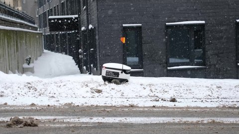 Tallinn, Estonia - December 4, 2021: Starship Technologies autonomous drone vehicle stuck in snow in winter. Starship self driving contactless food delivery robot.