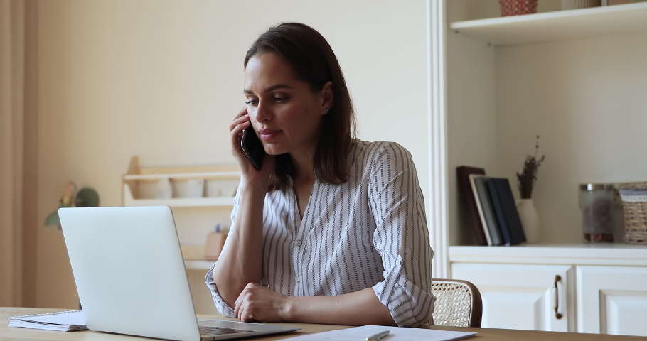 Remote job. Millennial woman work from home office use pc talk speak on phone offer goods service to client. Focused young lady freelancer discuss order details in telephone conversation with customer Royalty-Free Stock Footage #1083397273