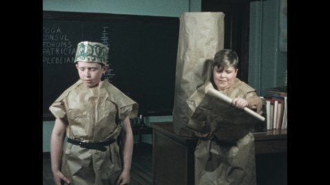 1950s: three boys in front of class dressed in brown paper Roman toga costumes performing play