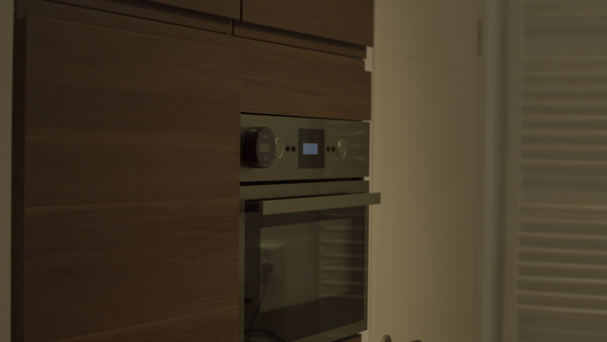 Woman opening fridge door in a modern kitchen, grabbing item and walking away