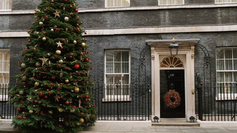 LONDON, DEC 2021 - Establishing shot of 10 Downing Street with the traditional Christmas tree and door wreath decoration in Whitehall, London, UK
