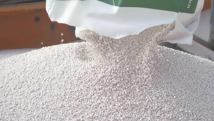 Grain of mineral fertilizer being unloaded from a plastic bag into a tractor trailer