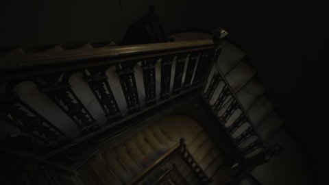 Tilt into overhead view of old wooden staircase leading in the darkness. Old brown rustic stairwell descending into darkness