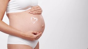Young, happy and healthy pregnant woman on white background. Studio video. Baby expectation, pregnancy and motherhood concept.