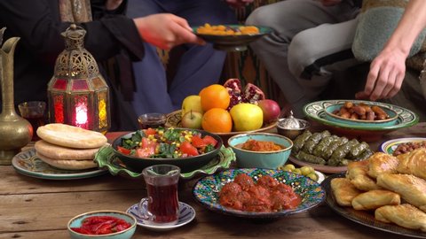 Middle Eastern muslim family eating together. Fasting, prayer and iftar during Ramadan in lockdown. Traditional Eastern and Asian food on the table