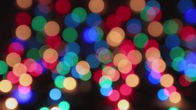 Multi-colored lights flickering on a black background, copy space. Greeting card for Christmas, New Year, Birthday. Festive video for intro, transition, splash screen. Copy space. UHD 4K.