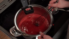 A professional confectioner adds spice leaves to the jam on the induction hob. Webcam recording of a step-by-step recipe for cooking Christmas cake