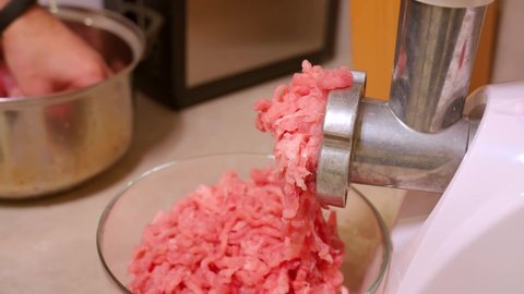 Making homemade raw minced meat at kitchen. Electric meat grinder.