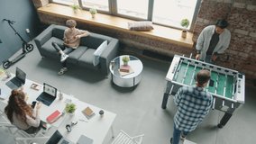 Happy young people are relaxing during work break playing ping pong and foosball in office. Modern youth lifestyle and positive emotions at work concept. - Powered by Shutterstock - Get 15% off with code: PIKWIZARD15