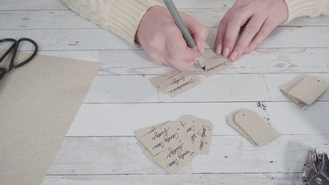 Step by step. Cutting out gift tags from brown paper with a paper punch.