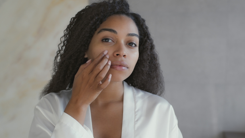 Beauty care procedures. Mirror pov of young attractive african american lady applying moisturizing cream on her face, taking care about her appearance at home, slow motion | Shutterstock HD Video #1083449149