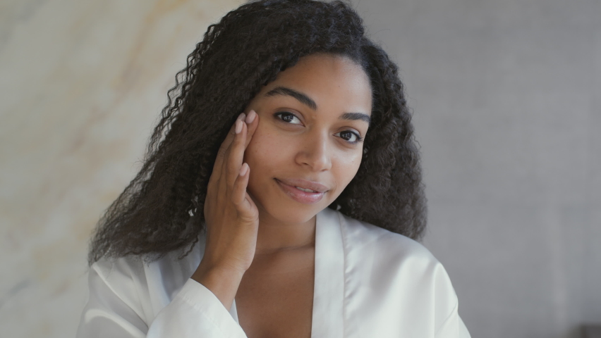 Beauty care procedures. Mirror pov of young attractive african american lady applying moisturizing cream on her face, taking care about her appearance at home, slow motion Royalty-Free Stock Footage #1083449149