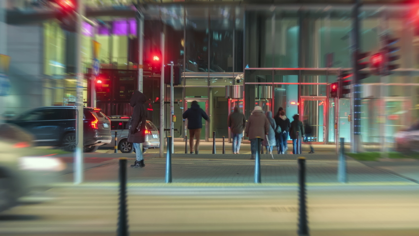 Time-lapse busy crossroad car traffic jam unrecognizable people crossing street at night, trams moving fast in city in evening. Timelapse cars rush hour drive way, pedestrians crossing intersection