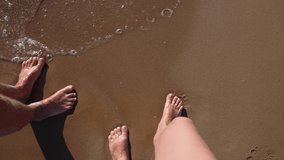 Top view from first person slow motion 4k video footage of barefoot male and female legs isolated on wet sandy sea beach background. Happy adult couple walking on sandy beach outside