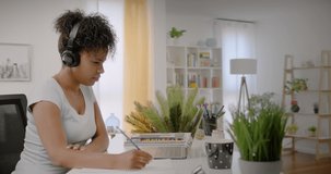 Lateral Dolly of Happy Young African American Woman Studying on Laptop Computer from Home. Remote Learning or Webinar Concept at Home Office.