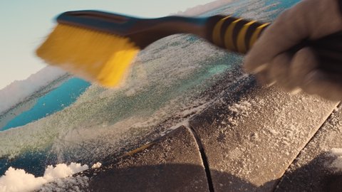 They sweep snow from a frozen car with a brush, preparing the car for a trip in the winter season. Problems of the Nordic countries in everyday life The hard life of a driver in snow and ice in winter