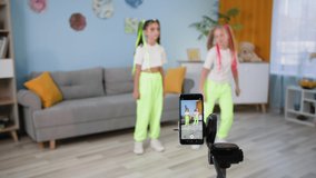 popular hobby, stylish female bloggers are filming in portrait orientation dance videos for modern social networks while sitting at home during quarantine, showing class on camera