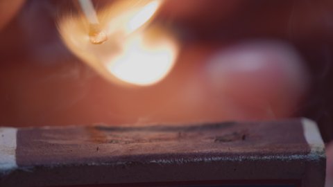 Matchstick with fire on the tip. Matchstick fires on Matchbox in macro slowmo. Macro Shot of Igniting Match against Black Background. Burning match, bright firelight