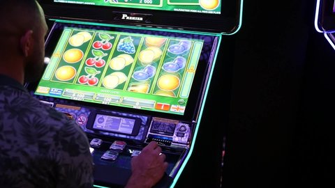 Batumi, Adjaria, Georgia - 11.28.2021: A man playing a slot machine. Slot screen with lemons close up.