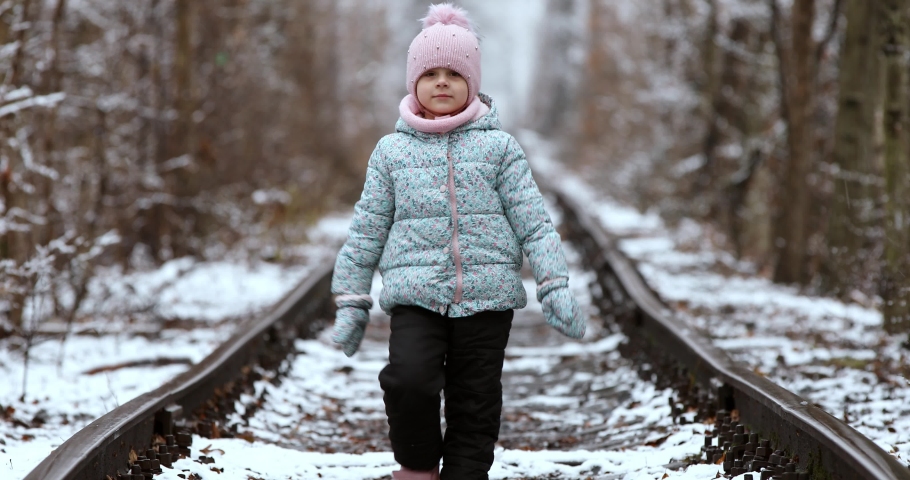 girl walks on rails in winter.
