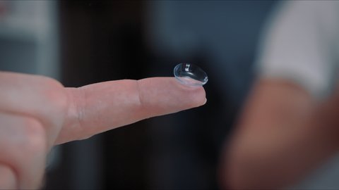 Contact lens on man finger, Correction of myopia eyesight concept