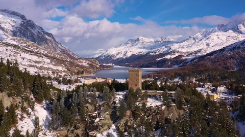 Aerial drone footage of the ancient fortification at the top of the Maloja pass in the alps in canton Graubunden in winter in Switzerland. Shot with a forward motion toward lake Sils in the back. 