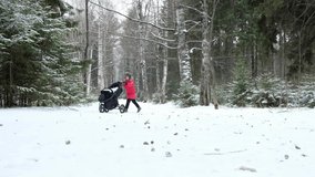 The older brother is walking with his sister. A child rolls a stroller in a snowy winter forest. High quality 4k footage. 4K video 3840x2160