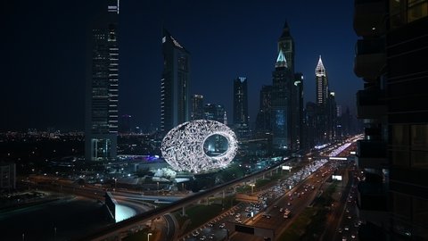 Museum of the future with lights on at night. Wide shot. Skyline and highway traffic.
Dubai, UAE - October, 2021