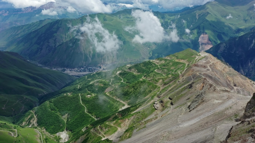 Aerial view on Caucasus mountains with roads and small town under clouds, Kabardino-Balkaria, Russia, 4k