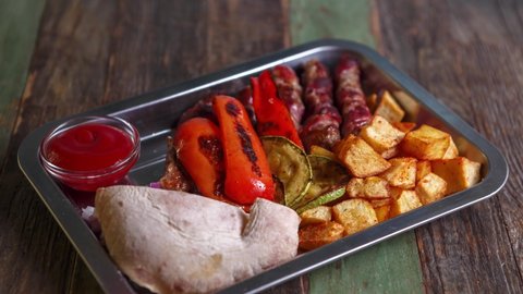 Bbq food video of Serbian meal cooked on grill in restaurant. Cevapcici, grilled vegetables, baked potatoes and home baked bread