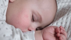 Peaceful adorable baby sleeping on his bed in a room at home. Sleeping newborn baby concept. 6 month-old baby girl sleeps at home. A serene dream. Face Close Up.