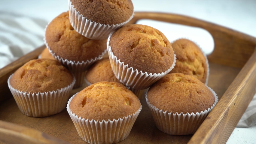 Muffins - delicious pastries. Baked dessert on the tabletop view. Homemade muffin. Portioned cupcakes. Simple food for party. Close-up muffins on a wooden tray.