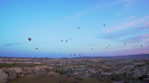 Amazing unusual landscape of turkish Cappadocia. Many hot air balloons full of happy tourists flying in blue sunrise morning sky over spectacular unusual lands of Kapadokya, Holidays, vacations, Turkey
