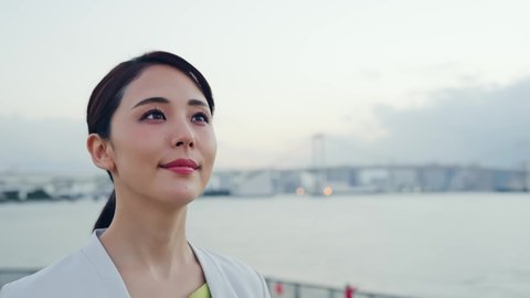 Young asian businesswoman staring into the distance in front of the city.