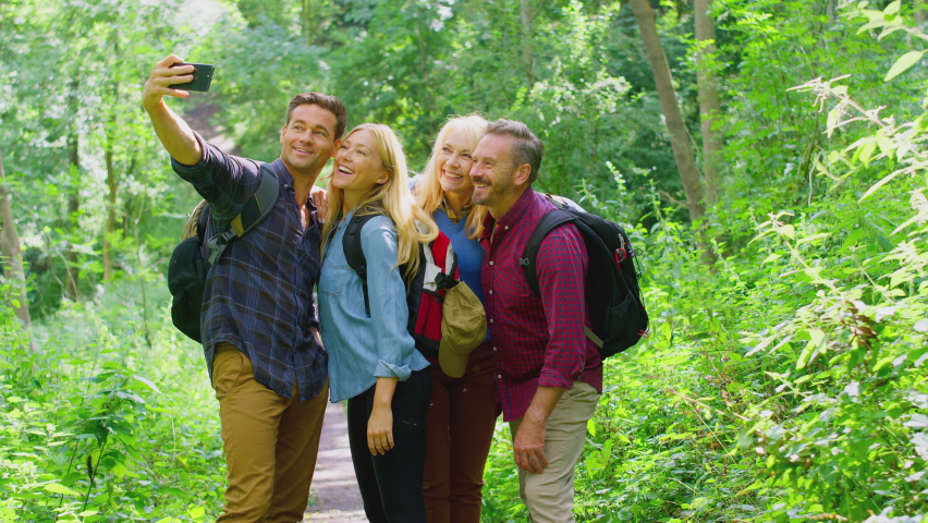 Group of friends taking photos and posing for selfie on mobile phone as they hike through countryside together - shot in slow motion Royalty-Free Stock Footage #1083499018