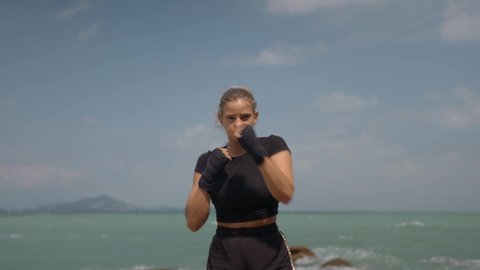 Close up shot of female making strong punches, she practicing muay thai outdoors