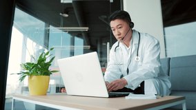 Asian male doctor advises patient online via video call using laptop and webcam with headset. Remote consultation with physician. man talking conversation chat Telemedicine, telehealth. surgery office