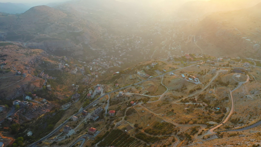 Aerial Panning Scenic Shot Of Built Structures In Village On Mountains Against Cloudy Sky During Sunset - Faraiya, Lebanon