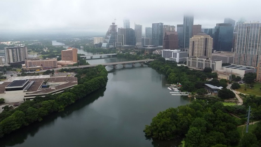 Aerial Shot Of Bridge Over Colorado River By Modern Buildings, Drone Flying Forward Towards Vehicles In City Under Foggy Weather - Austin, Texas