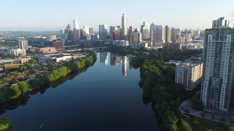 Aerial Shot Of Modern Buildings Reflection On Colorado River, Drone Flying Forward Over City Against Sky On Sunny Day - Austin, Texas