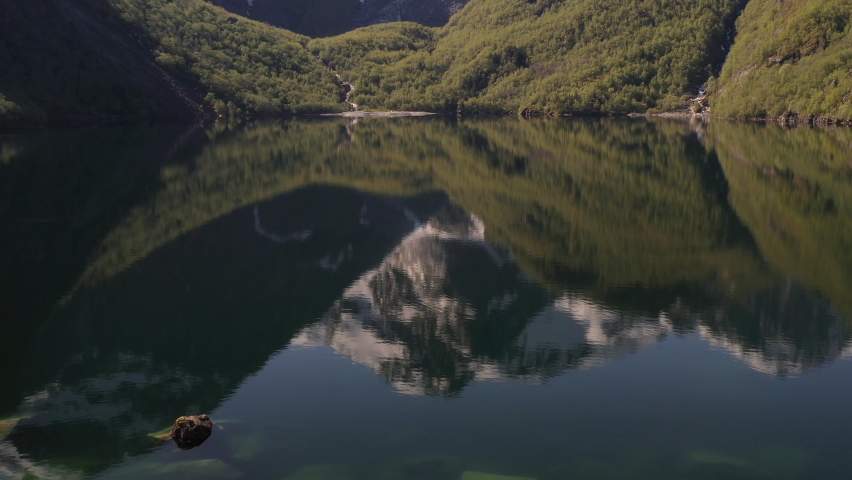 Flying backwards over Bondhus Lake in Norway. Slow tilt upwards with glacier in background