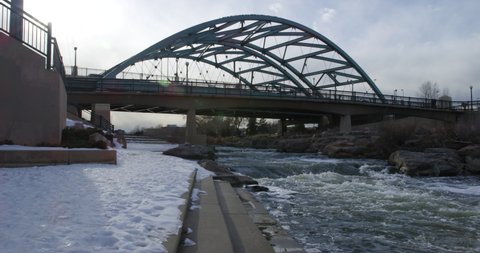 Speer Boulevard Bridge Over South Platte River In Denver, Colorado With Snowy Riverbank In Winter. panning right
