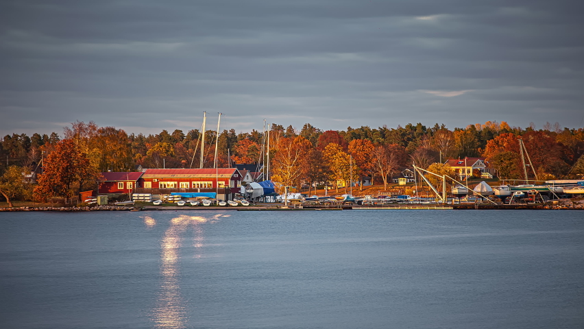 Time lapse shot of grey flying clouds over sailing boat harbor during sunset in the evening - Tranquil water of lake during autumnal day