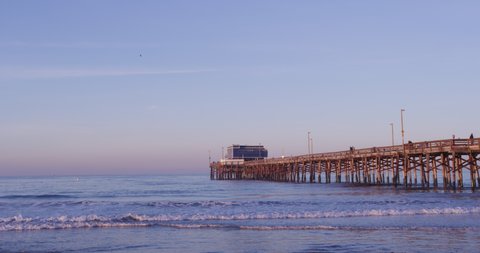 Ocean Waves At Shoreline Of Beach With Fishing Pier At Dawn In Newport Beach, California, USA. - wide shot