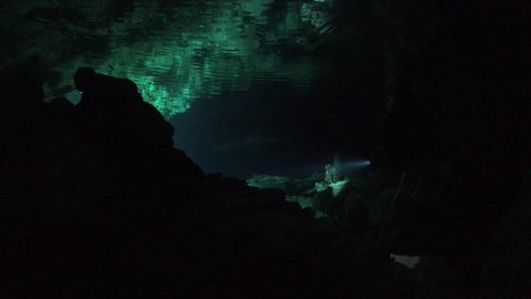 Scuba Divers in Cave system Cenote Tajma Ha in Yucatan Mexico and reflection on water surfacce