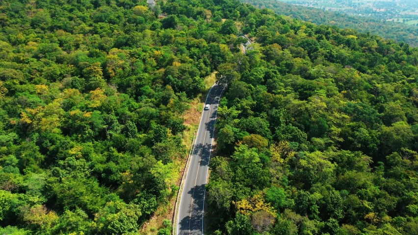 Aerial view from top to bottom of a white car driving on a mountain country road in clear daytime. Cinematic drones shot over mountain road roads. One car driving on with a beautiful landscape Royalty-Free Stock Footage #1083516703