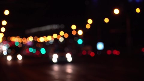 Reflects lonely capital city lifestyle. Round colorful bokeh shine from car lights in traffic jam on city street. Beautiful glittering bokeh in dark blurry background at night. Abstract concept. 