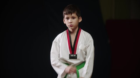 A little boy in white uniform doing taekwondo - standing in position and showing moves